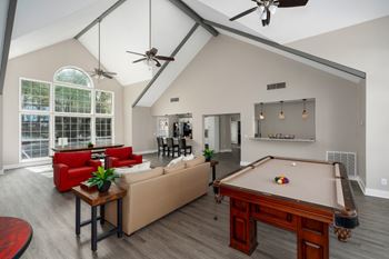 Clubhouse with a pool table, large windows, and ceiling fans.